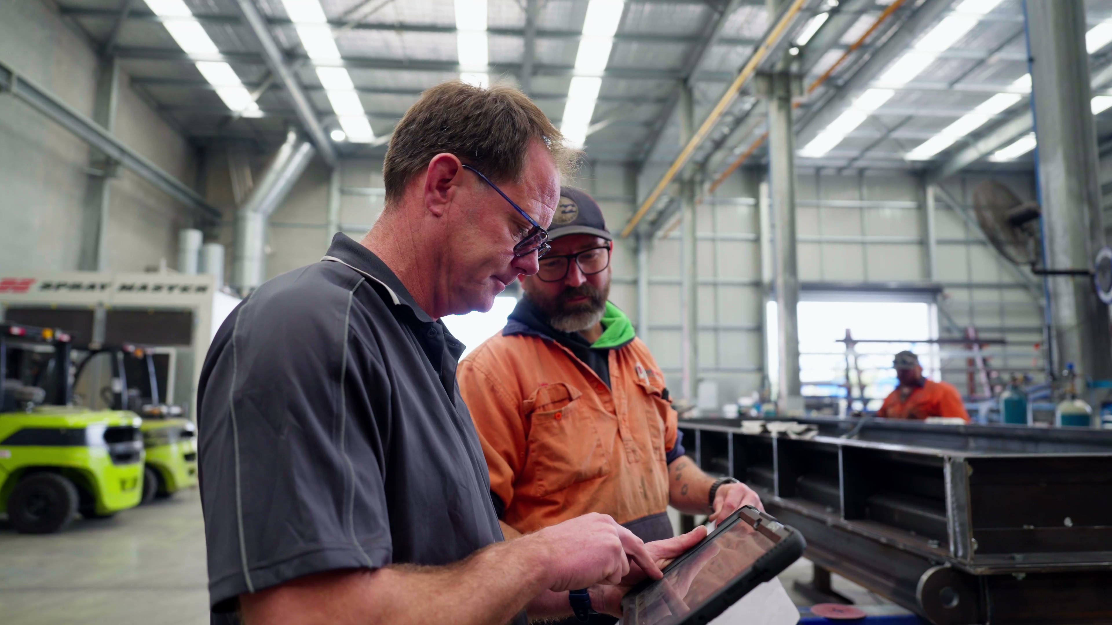 Two team members reviewing information together on a tablet on the shop floor