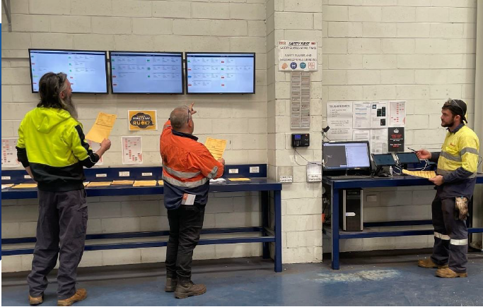 Shop floor team reviewing production information on wall-mounted displays