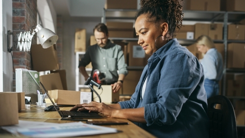 Product seller working at computer in warehouse office