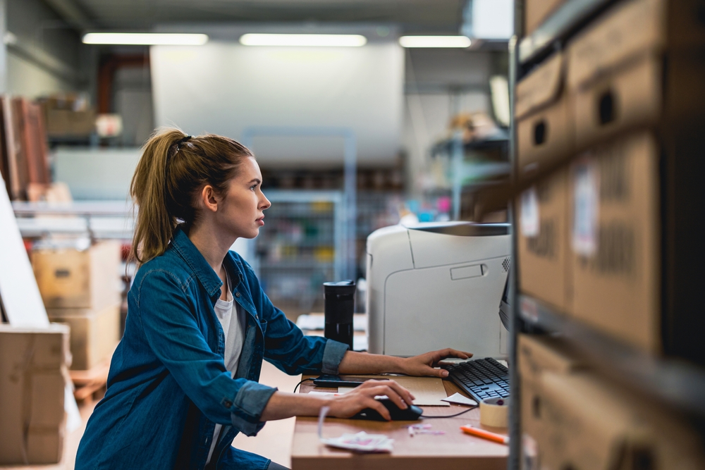 Sales assistant working at computer in warehouse office
